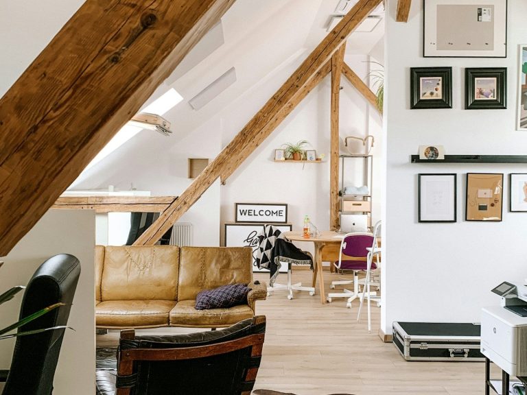 Spacious, modern living area with wooden beams, a sofa, and dining space.