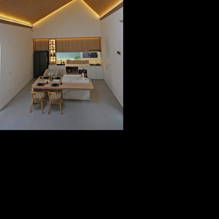 Modern kitchen with high ceilings, skylight, and minimalist wooden decor.