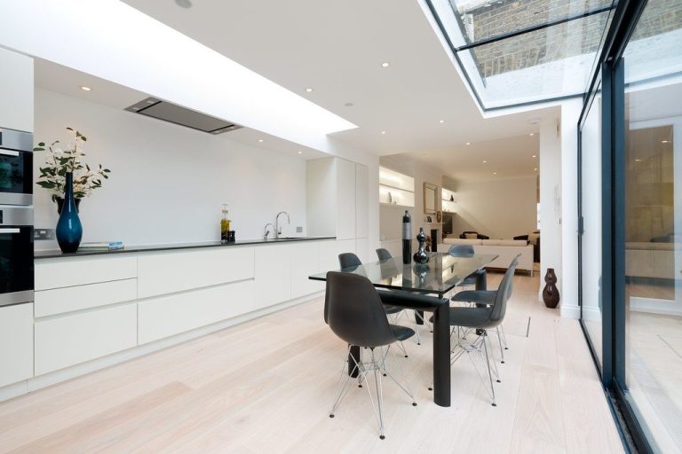 Side extension Modern kitchen and dining area with sleek furniture and large glass doors for natural light.