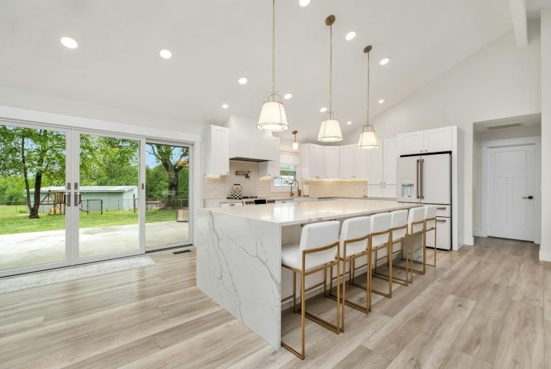 Kitchen extension Modern kitchen with marble countertops, stylish bar stools, and large sliding doors to a garden.