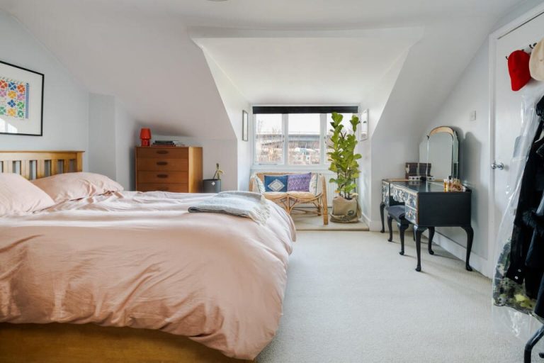 Loft Conversion and rear dormer Bright attic bedroom with a pink duvet, a mirror, and large windows overlooking a patio.