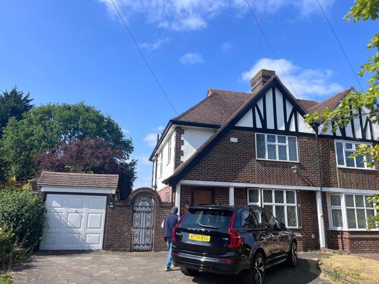 A Seamless Side Extension in Reigate & Banstead A semi-detached house with a garage and parked black SUV against a clear blue sky.