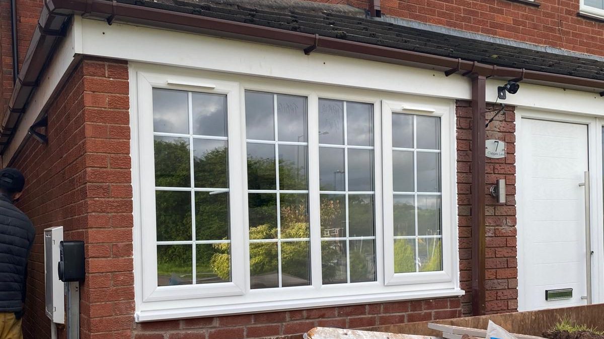 Garage conversion in Birmingham Modern glass-fronted extension with a wooden frame, set against a cloudy sky.