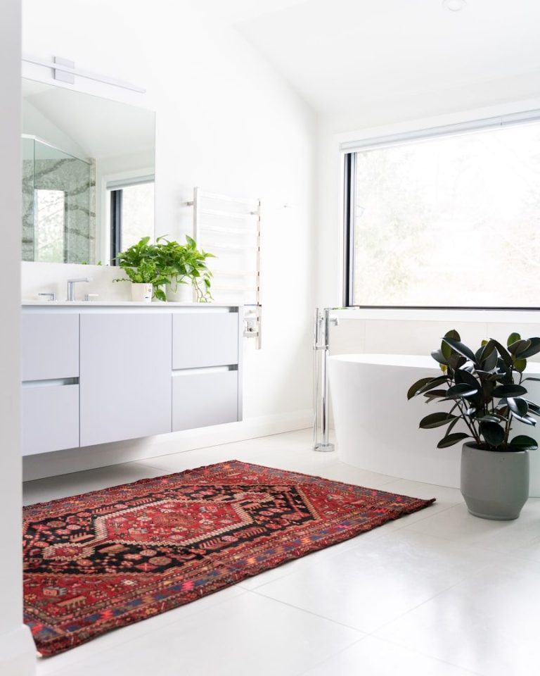 Bathroom A modern bathroom featuring a white bathtub, sink, and a red patterned rug.