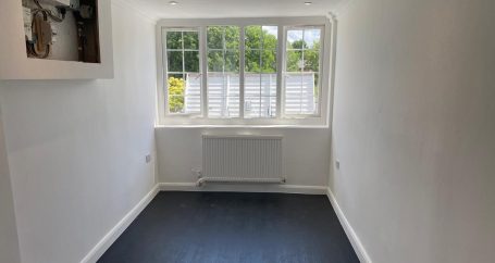 Garage conversion in Birmingham Empty room with a blue floor, large window, and a white radiator.