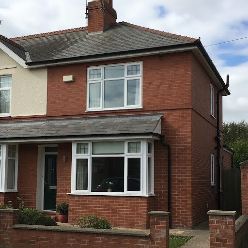 Red brick house with a grey roof, white windows, and small front garden.