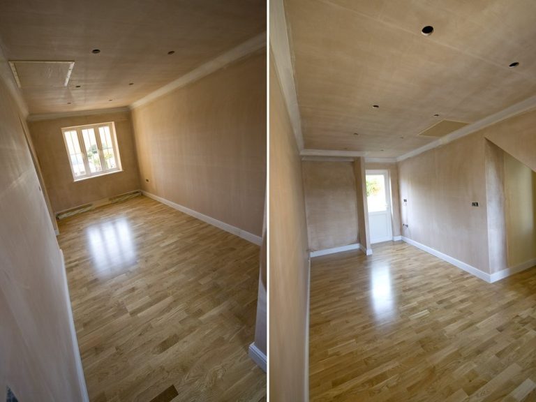 Garage Conversion Empty room with wooden flooring and light-coloured walls, featuring a window.